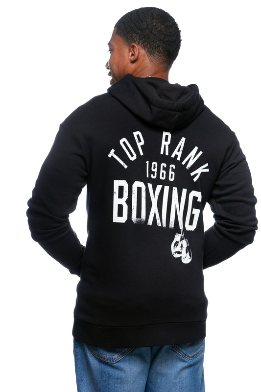 Person wearing a black hoodie with "Top Rank 1966 Boxing" printed in white on the back, paired with blue jeans.